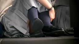 イベント会場で足を開いて体育座りしている制服スカートJK